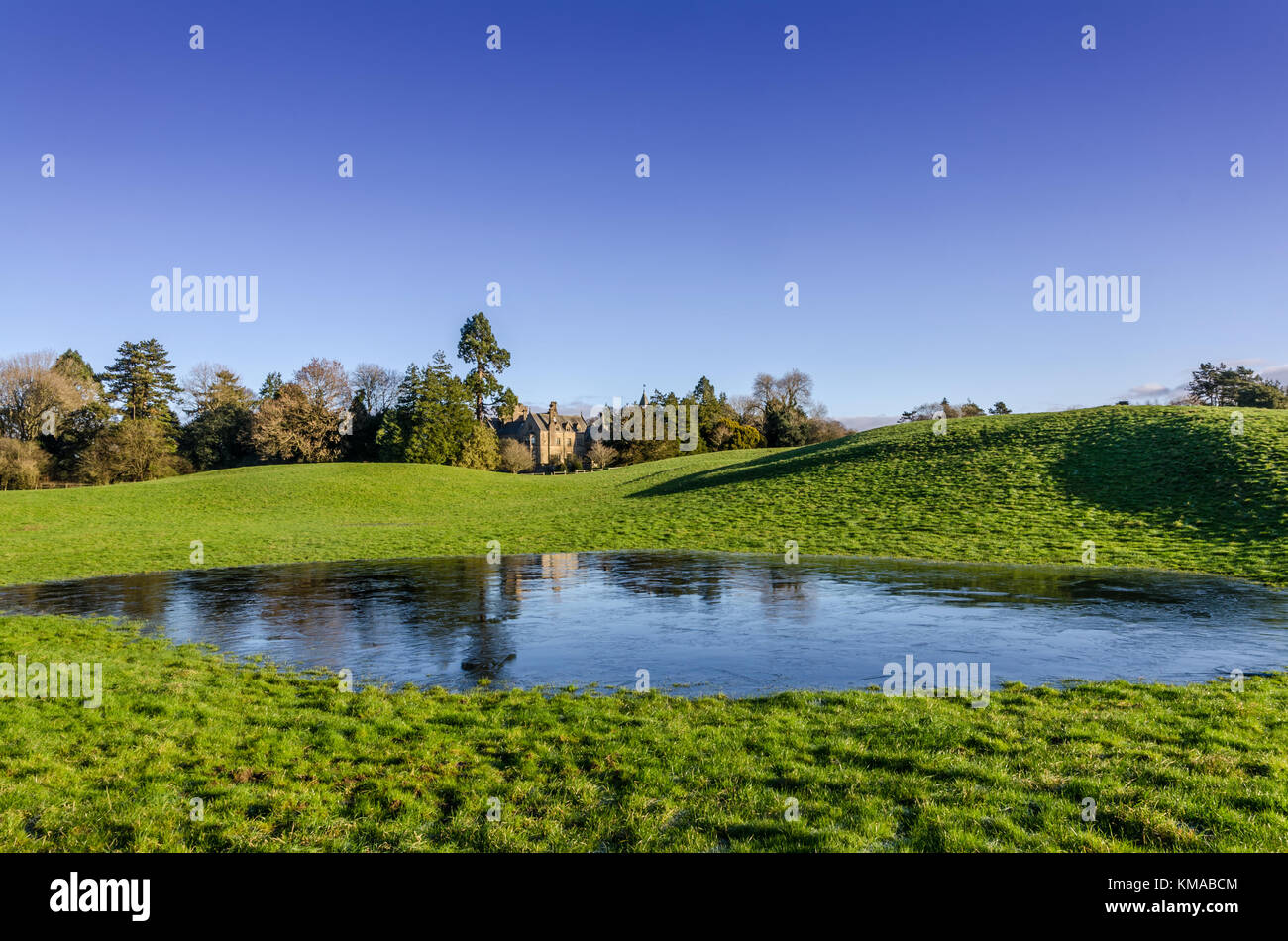 Ein Landhaus mit einem gefrorenen Teich im Winter. Stockfoto