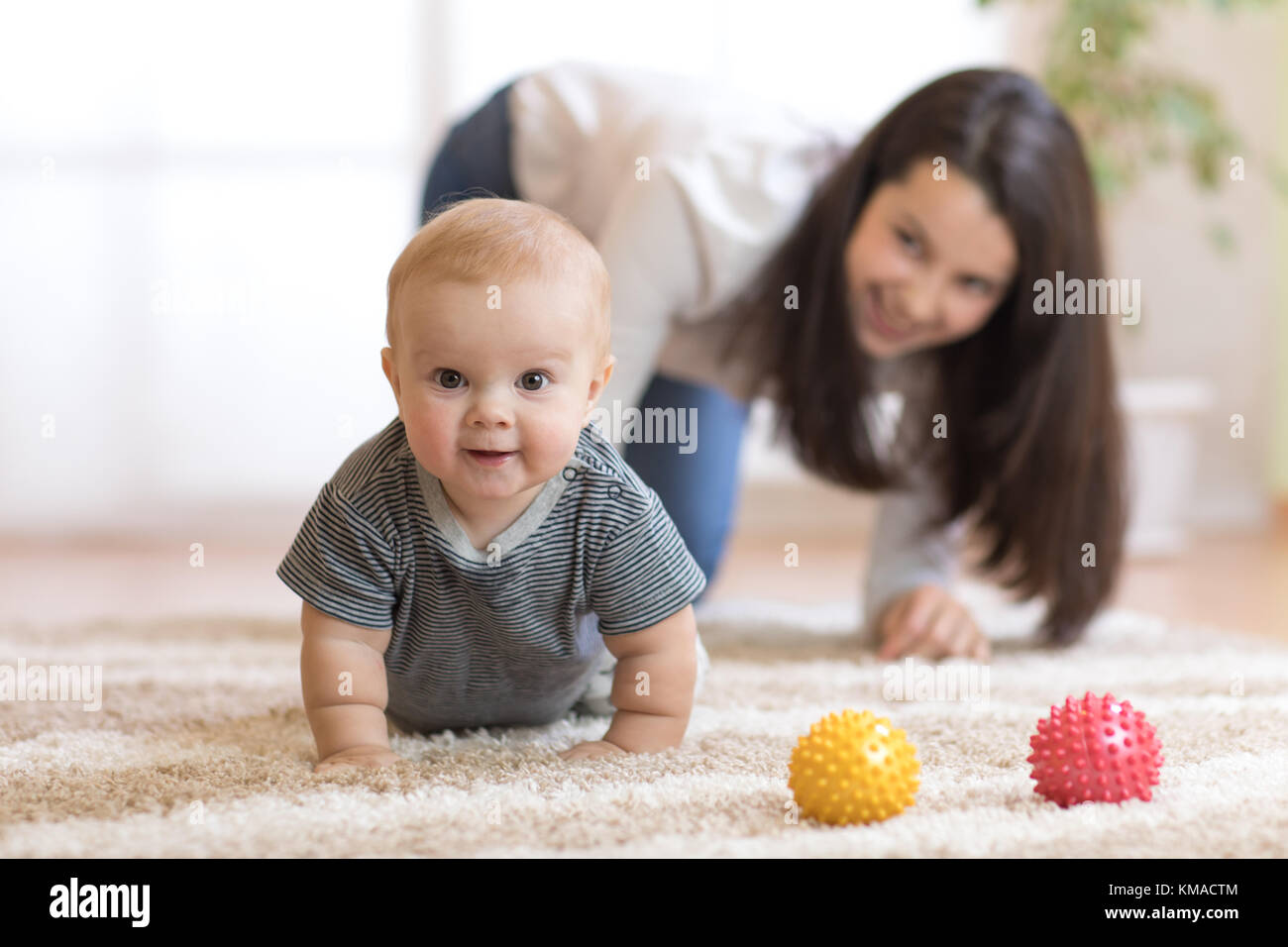 Lustige crawling Baby mit Mutter Stockfoto