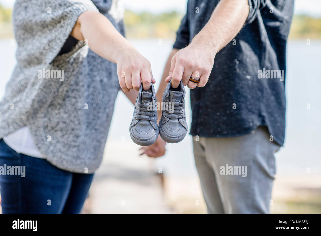 Paar macht Baby Ansage mit einem winzigen Paar Schuhe außerhalb auf einem Dock Stockfoto