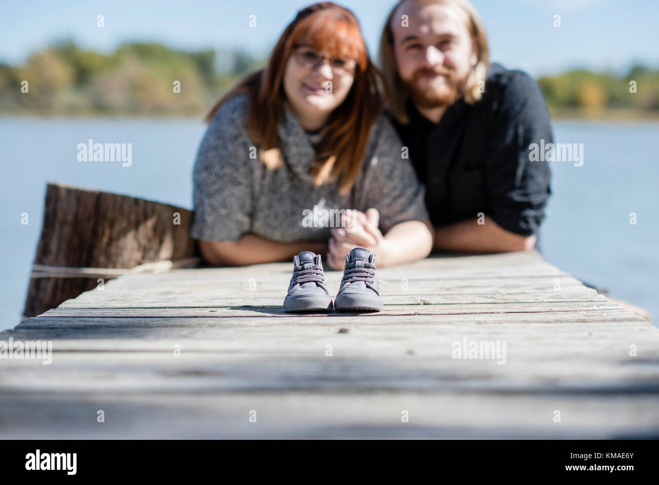 Paar macht Baby Ansage mit einem winzigen Paar Schuhe außerhalb auf einem Dock Stockfoto