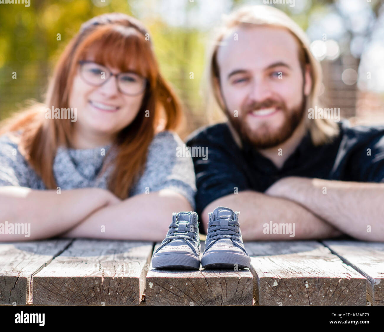 Paar macht Baby Ansage mit einem winzigen Paar Schuhe außerhalb auf einem Dock Stockfoto
