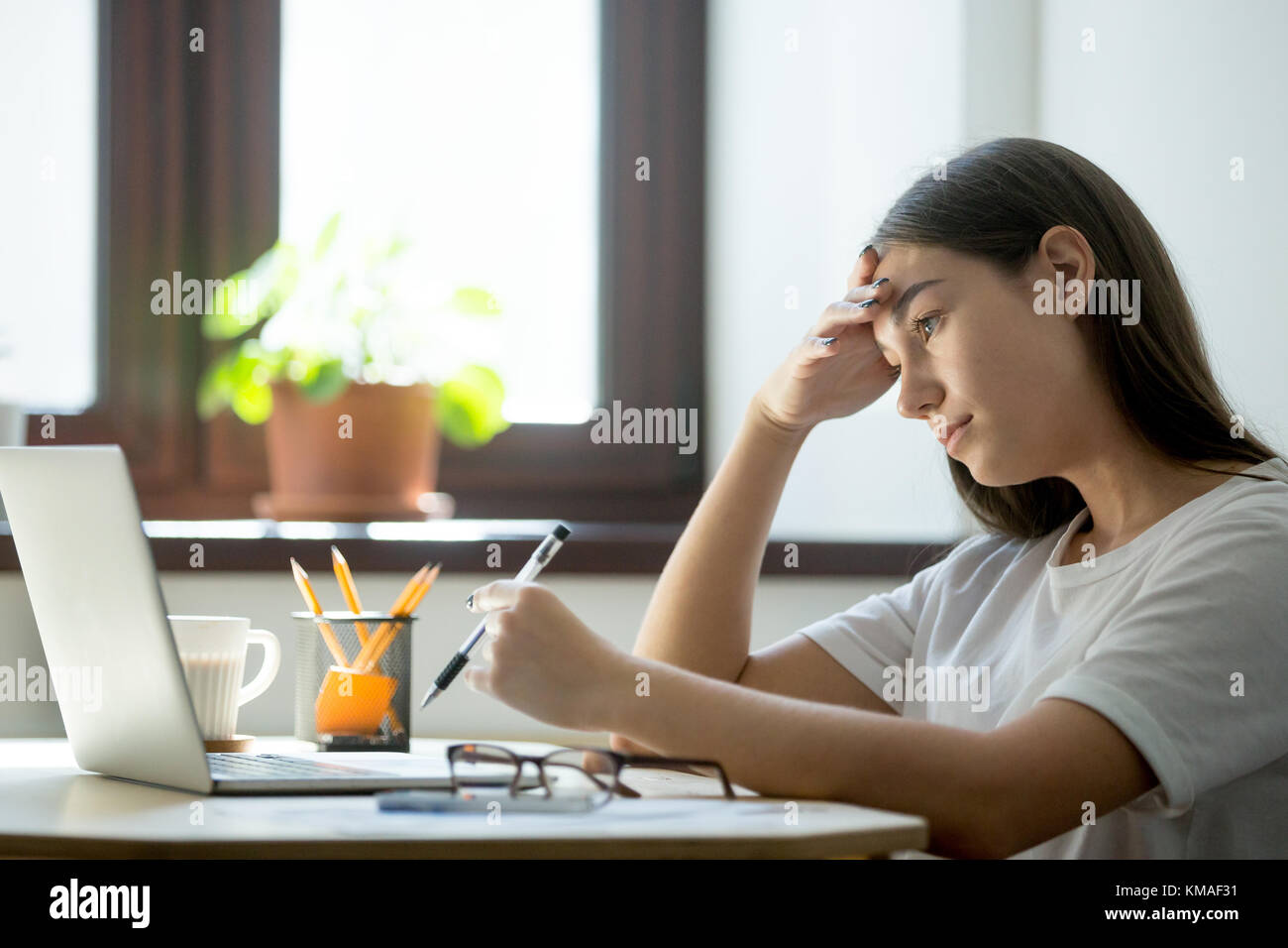 Mangel an Energie, Langeweile bei der Arbeit. Attraktive tausendjährigen Frau Studium auf Laptop und die Vorbereitung der Beendigung des Studiums. müde weibliche Freiberufler mit Stockfoto