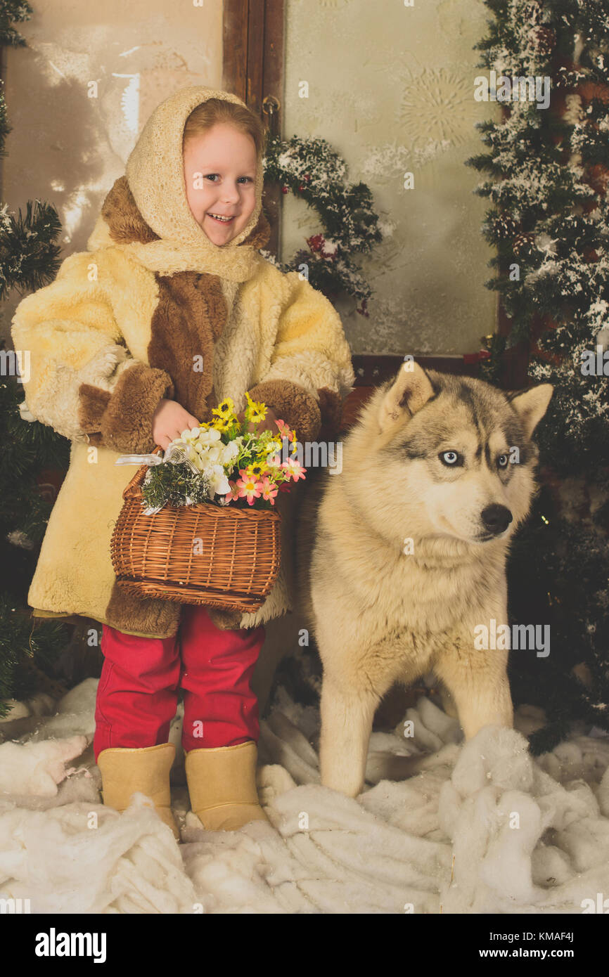 Ein kleines Mädchen, umarmen, einen Hund im Norden Rasse. Eine künstliche Innenbeleuchtung der Winter Forest Stockfoto