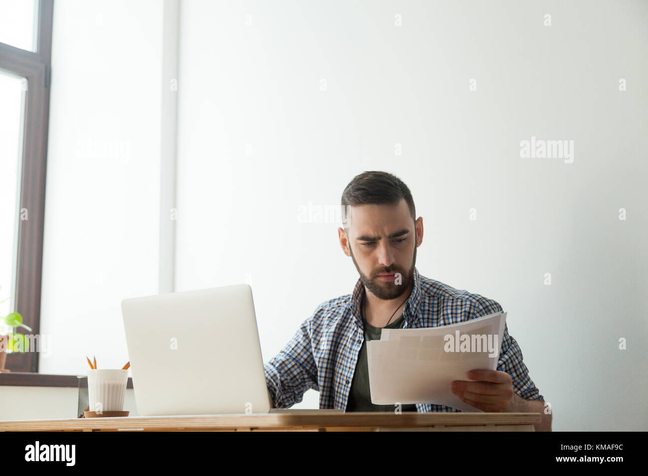 Tausendjährige hipster männlichen Designer holding Pantone Color Swatch Palette. Konzentriert man Arbeiten am Laptop und Home Design Stockfoto