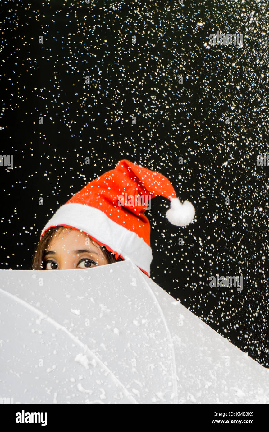 Junge Mädchen in der Mütze durch ein Regenschirm lugen. Stockfoto