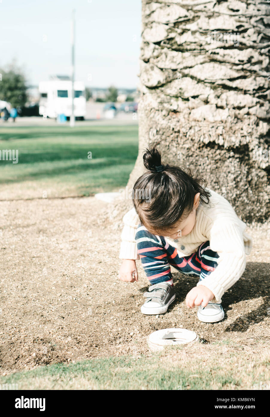 Kleinkind sammeln Gras in ein Abflussrohr Stockfoto