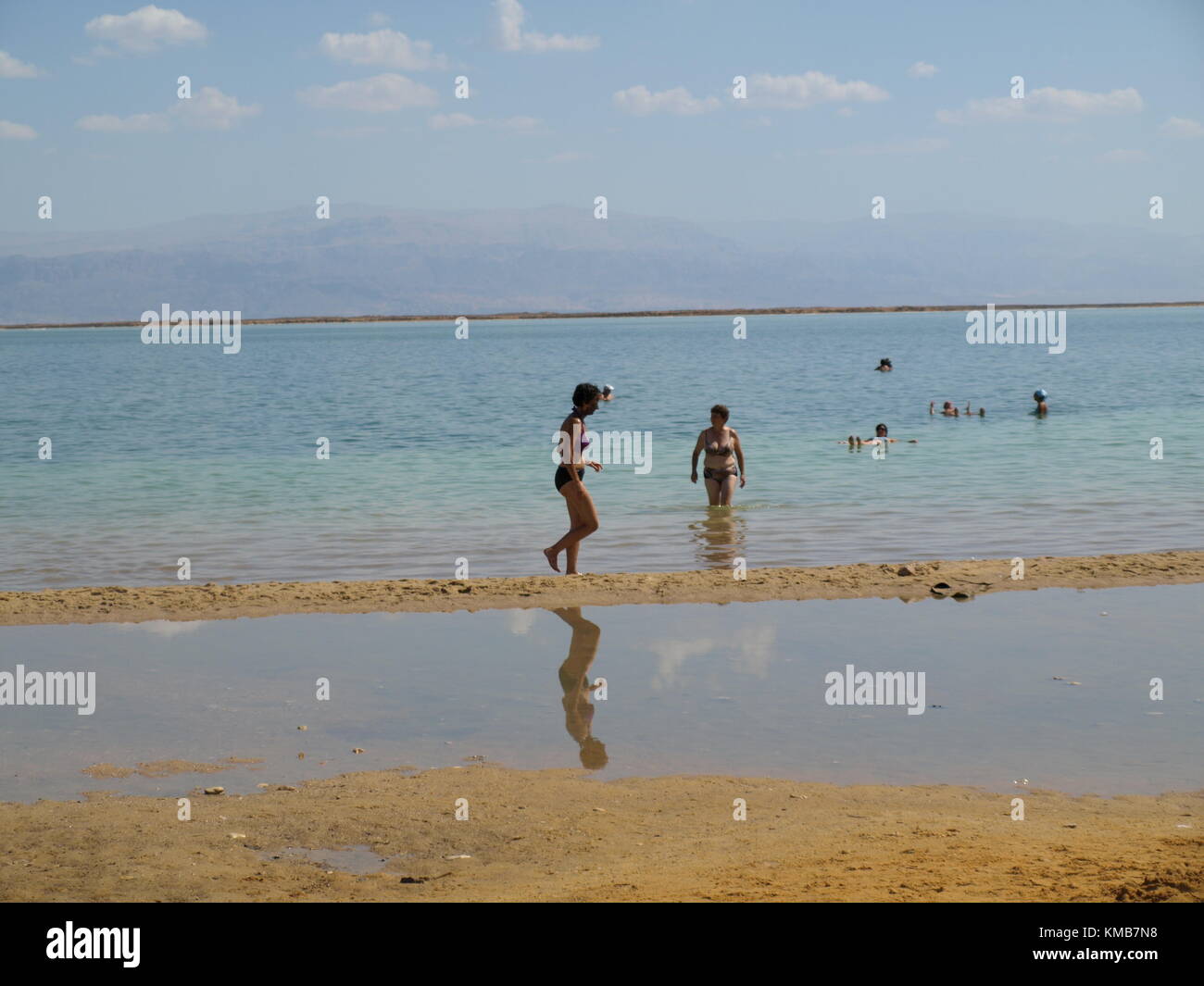 Eine Frau mit mineralischen Schlamm auf ihr Gesicht ist zu Fuß am Strand des Toten Meeres Stockfoto