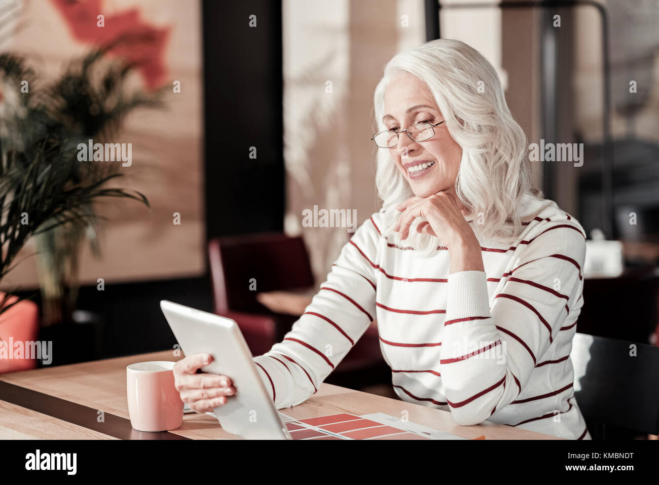 Progressive begeisterte ältere Frau auf dem Bildschirm eines Tablet suchen Stockfoto