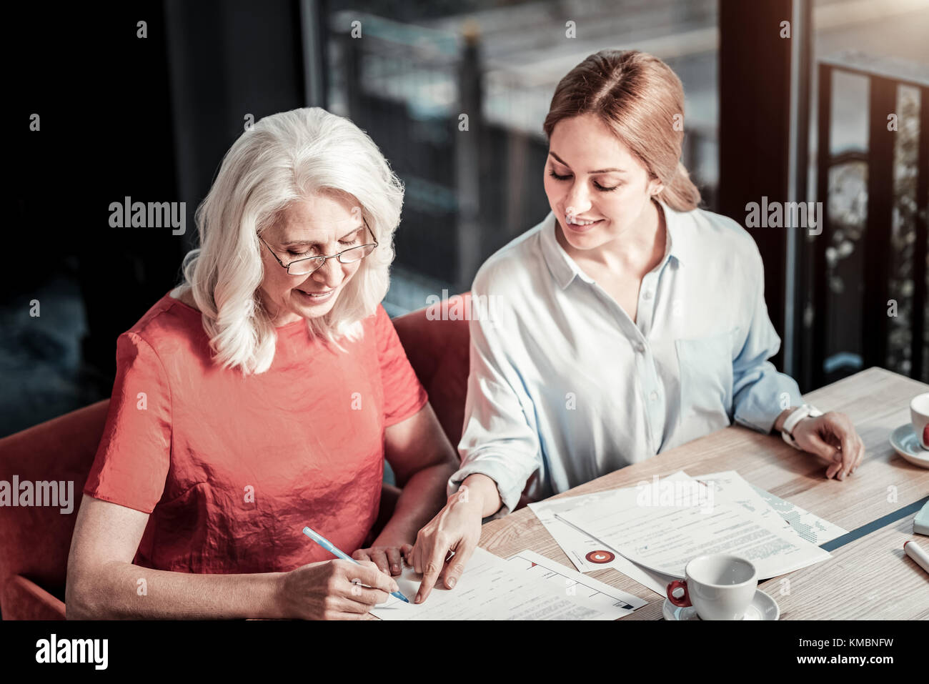 Freundlich lächelnde Frau, die auf den Platz für eine Unterschrift Stockfoto