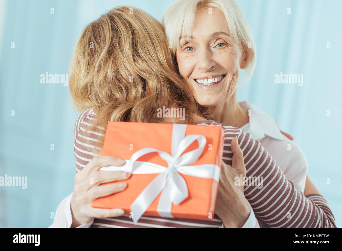 Aufgeregt Rentner mit einem präsentieren, während Ihr süsses Enkelin umarmen Stockfoto