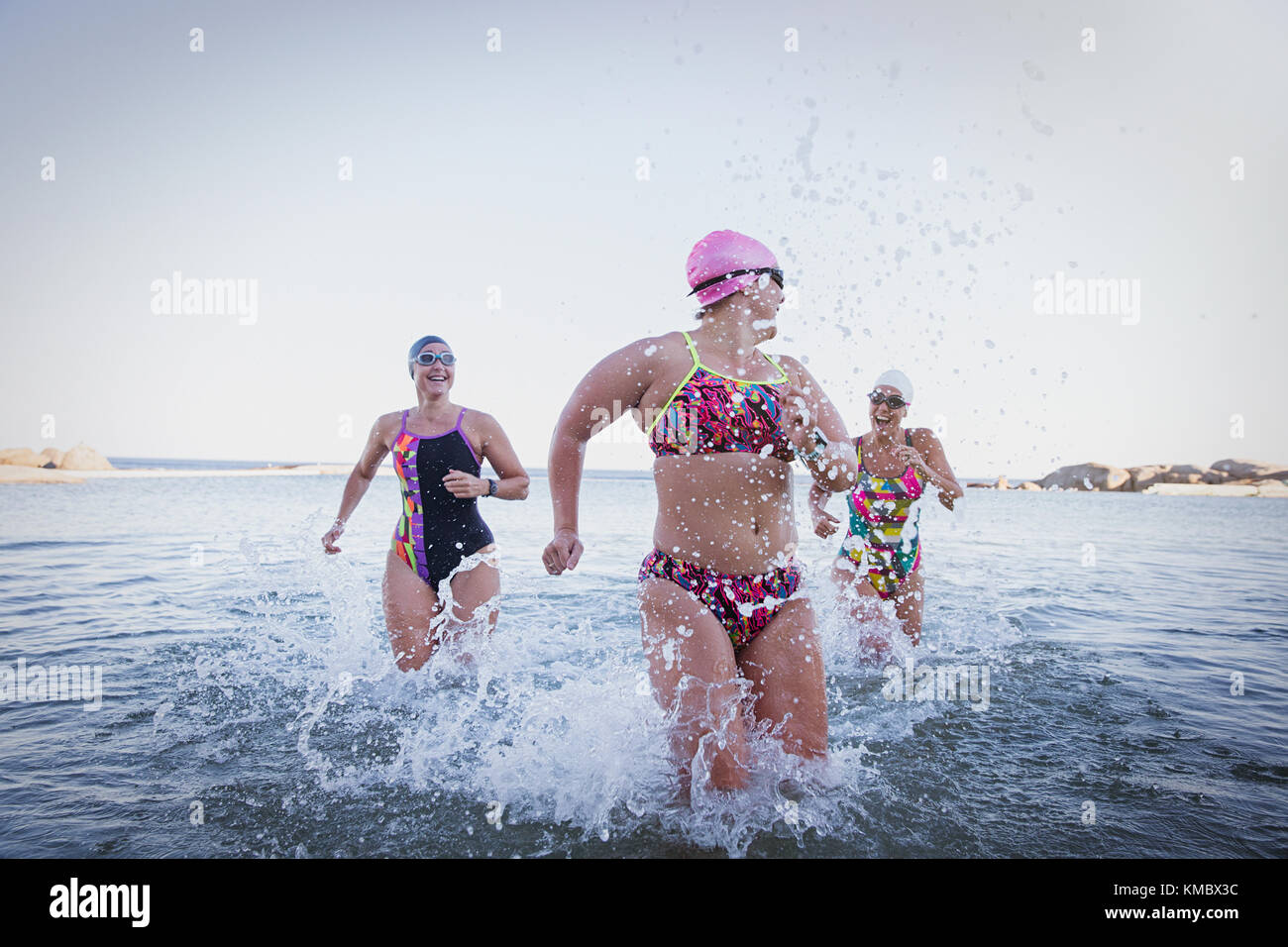 Weibliche Schwimmer im offenen Wasser laufen, planschen in der Meeresbrandung Stockfoto
