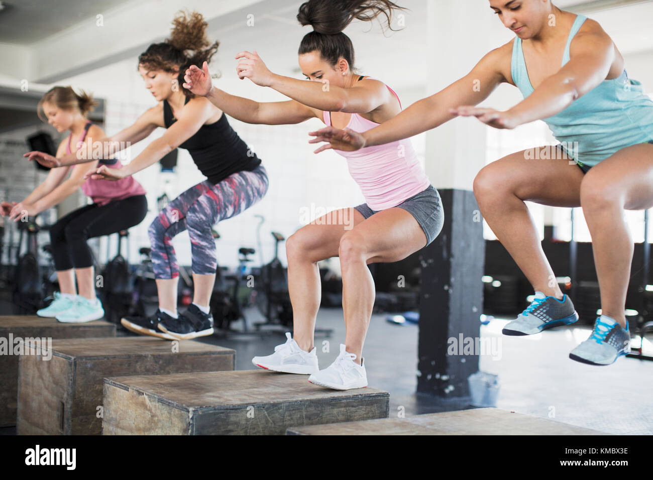 Entschlossene Frauen tun Sprung hockt auf Boxen in Übung Klasse Stockfoto