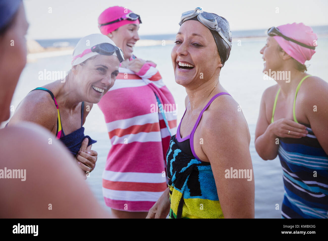 Lachend weiblichen Open water Schwimmer aus Trocknen mit Handtücher Stockfoto