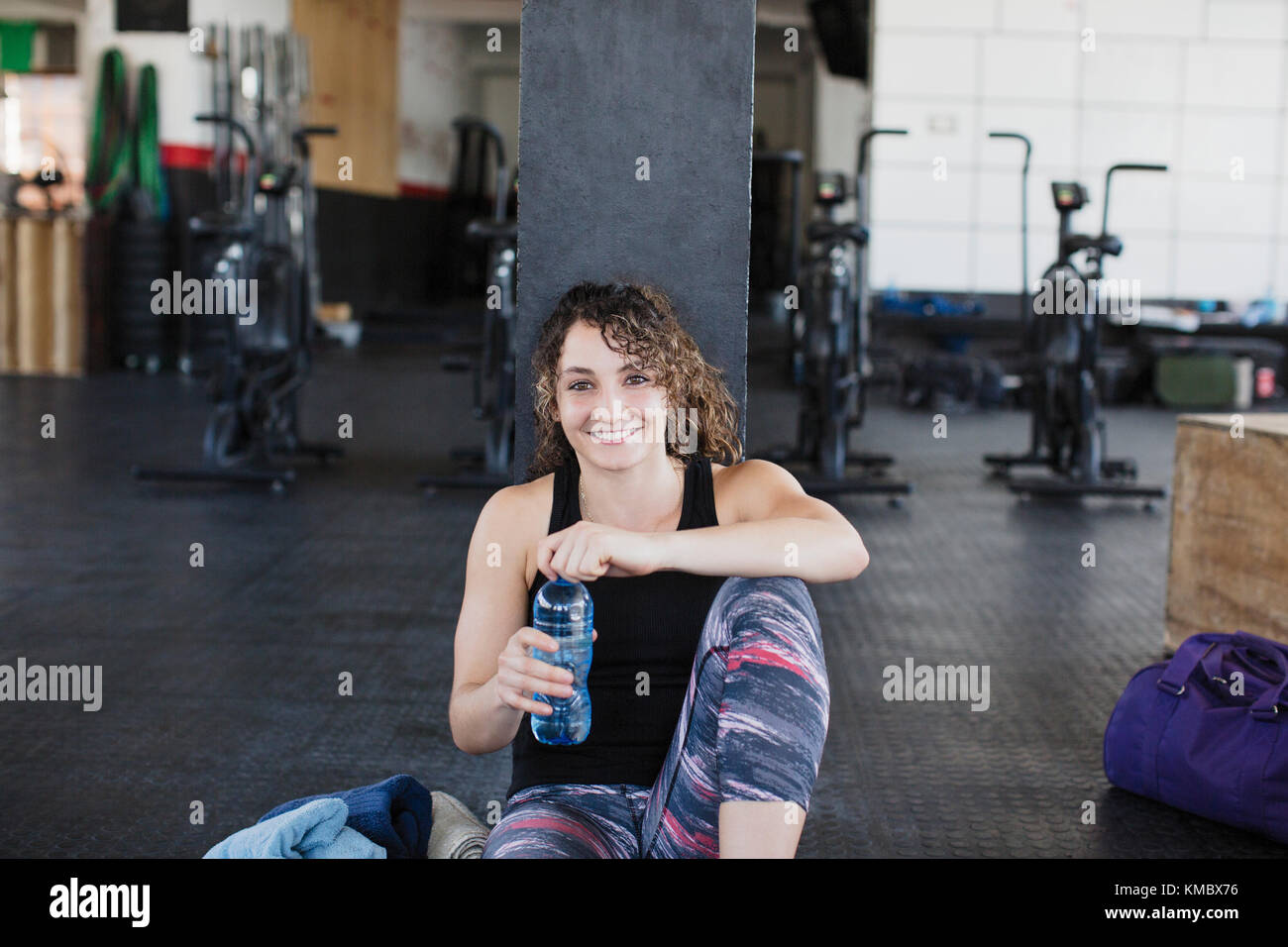 Porträt lächelnde, selbstbewusste junge Frau, die nach dem Training im Fitnessstudio Wasser trinkt und sich ausruhen kann Stockfoto