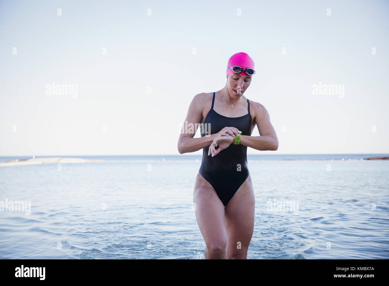 Weibliche Schwimmerin im offenen Wasser, die Zeit auf Smart Watch in überprüft meeresbrandung Stockfoto