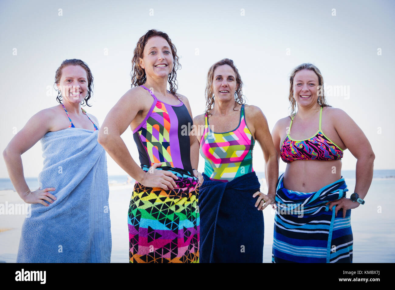 Portrait selbstbewusst, lächelnd weibliche Schwimmer im offenen Wasser eingewickelt in Handtücher Stockfoto