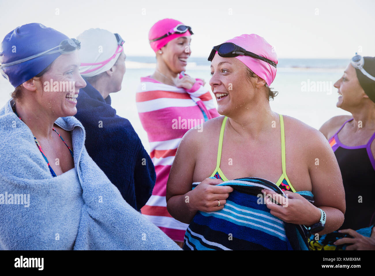 Weibliche Schwimmer reden und trocknen mit Handtüchern ab Am Strand Stockfoto