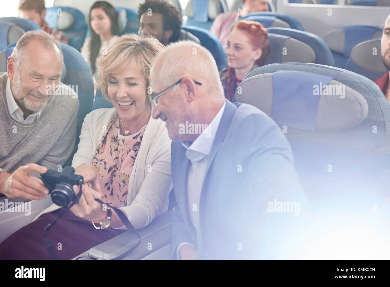 Lächelnde Freunde betrachten Fotos auf Digitalkamera im Flugzeug Stockfoto