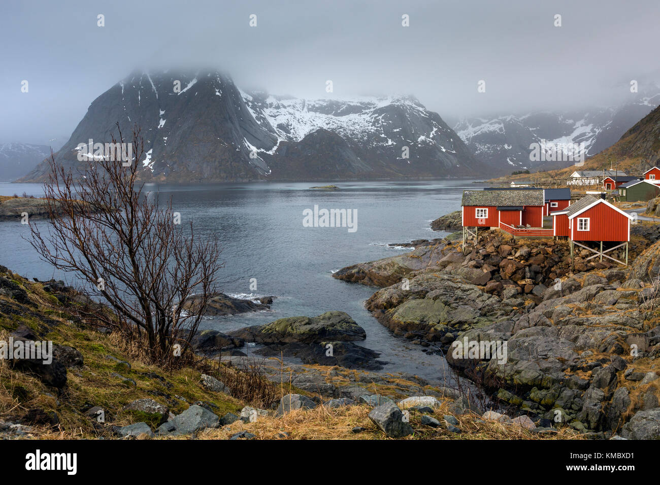 Fischerdorf am Wasser unter verschneiten, zerklüfteten Bergen, Hamnoya, Lofoten, Norwegen Stockfoto