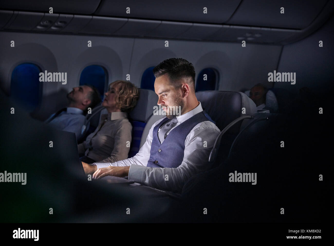 Geschäftsmann, der im Nachtflugzeug am Laptop arbeitet Stockfoto