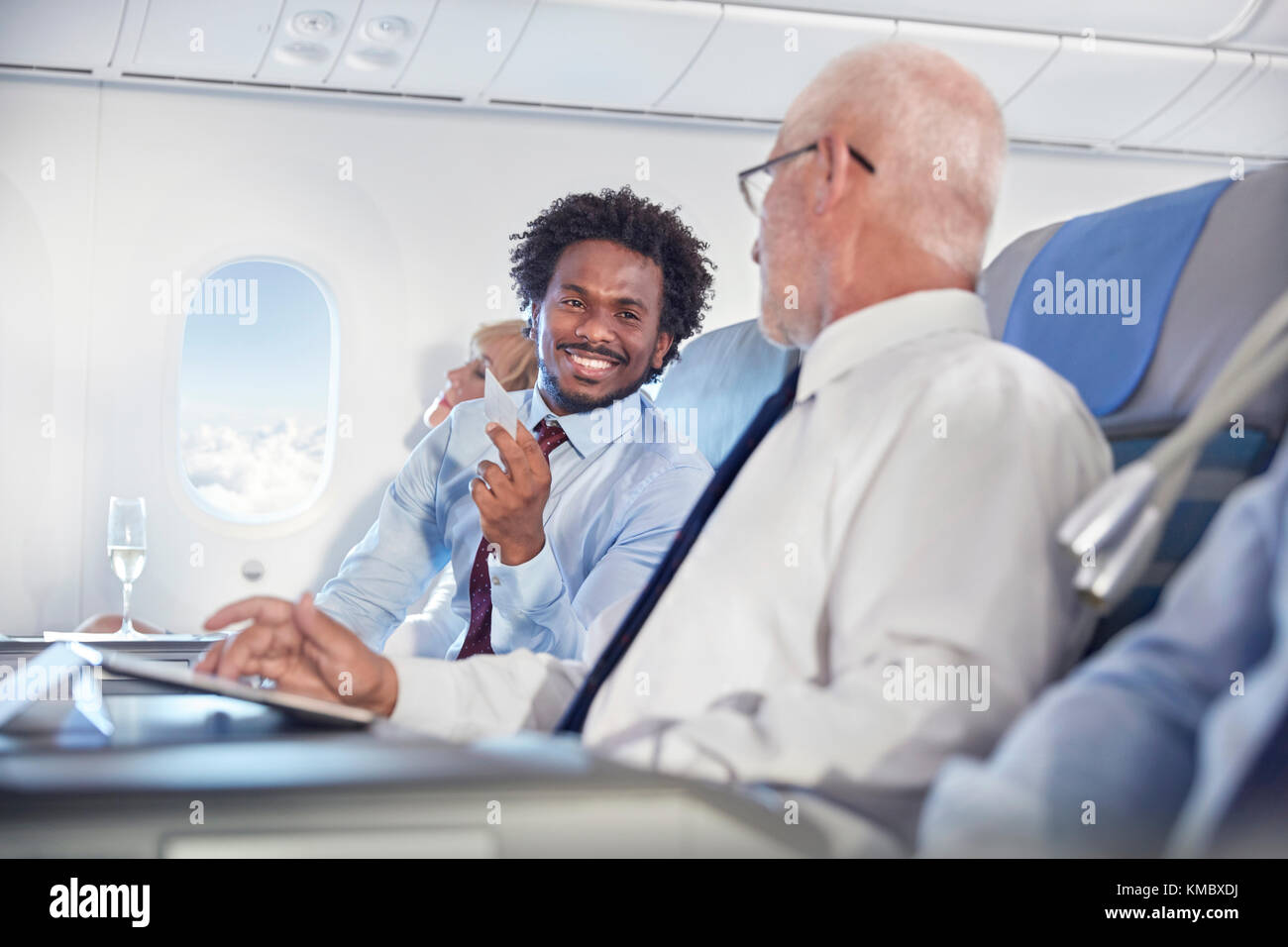 Lächelnde Geschäftsleute tauschen Visitenkarten im Flugzeug aus Stockfoto