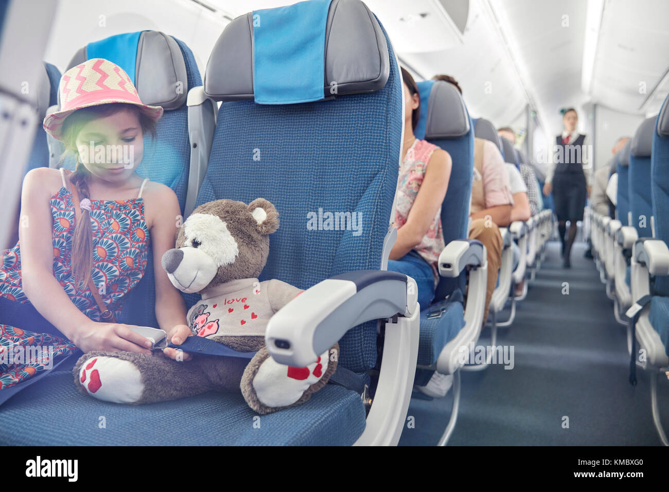 Mädchen Befestigung Sicherheitsgurt auf Stofftier im Flugzeug Stockfoto