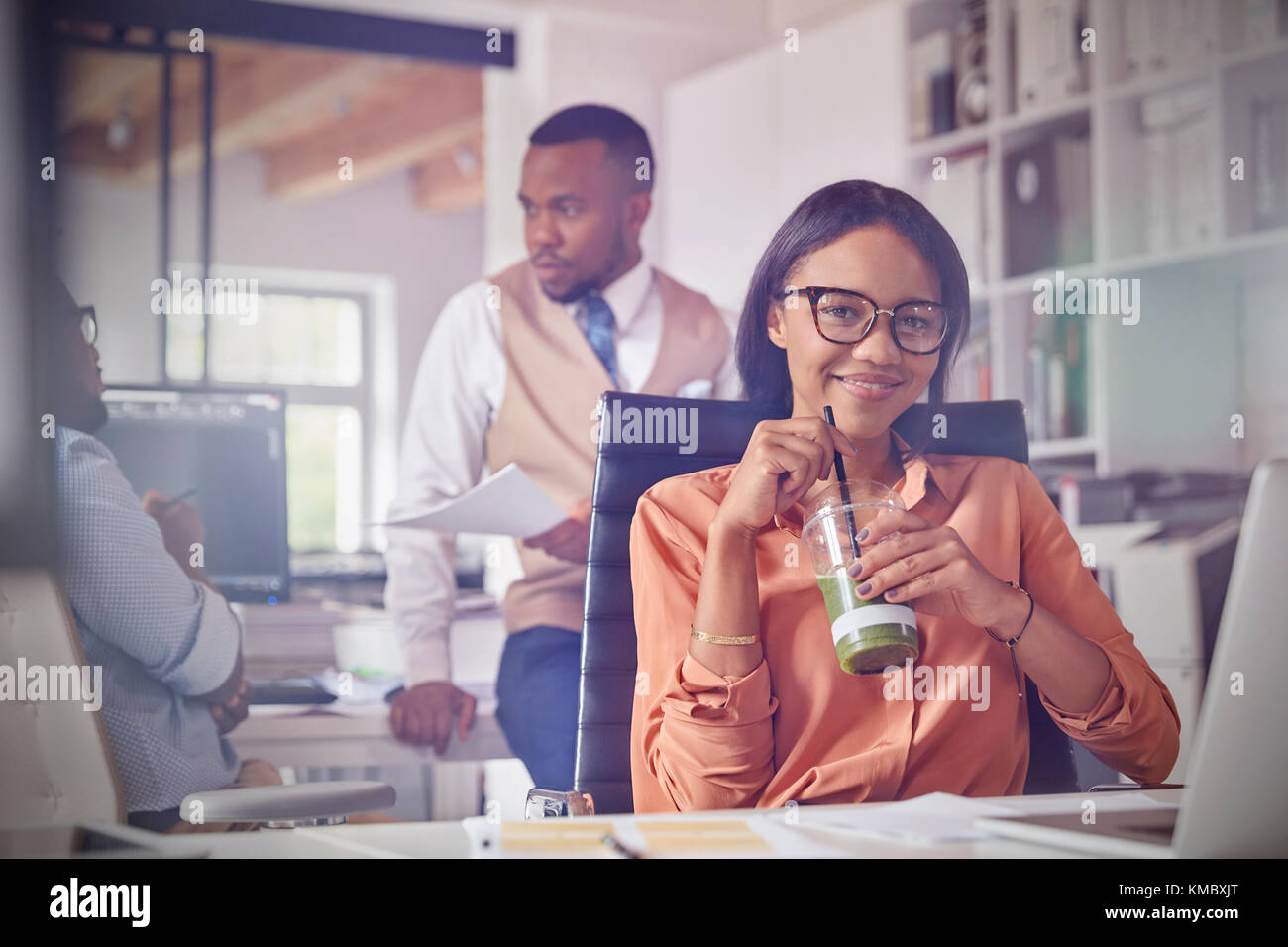 Porträt Lächeln zuversichtlich Geschäftsfrau trinken grünen Smoothie im Büro Stockfoto