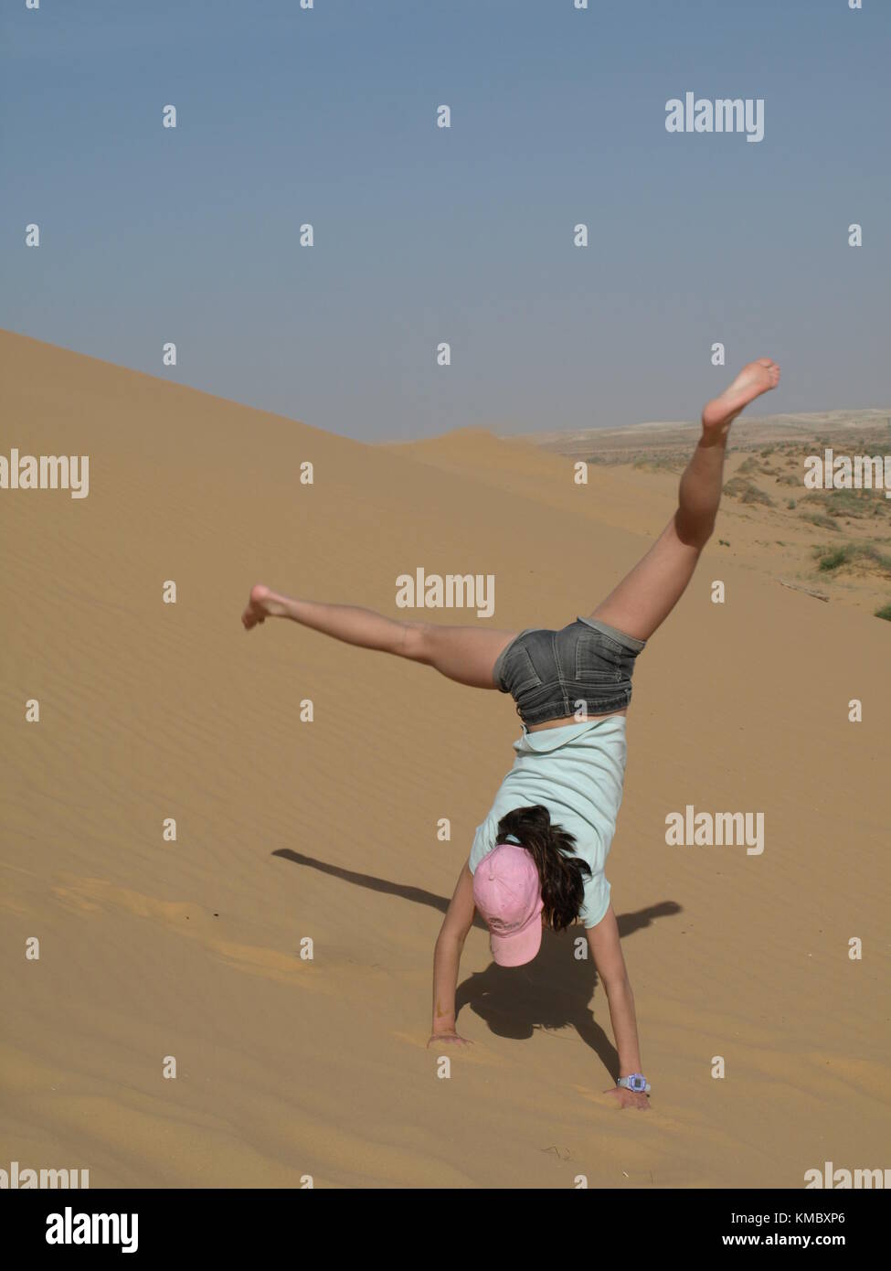 Stehendes Mädchen auf ihre Hand auf einer Sanddüne Stockfoto