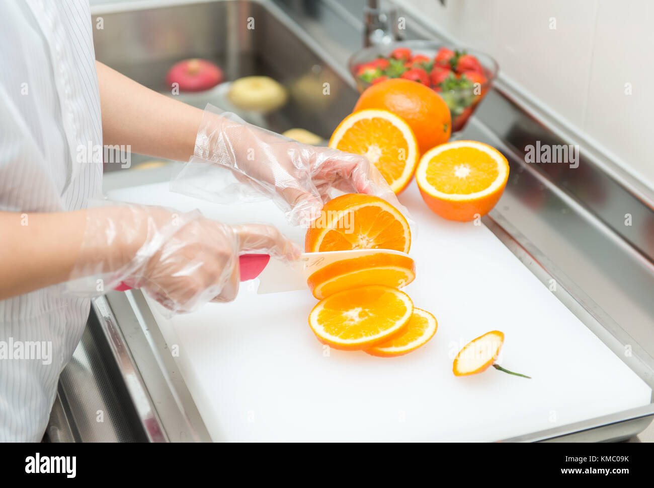 Weibliche Hände schneiden Frische saftige Orange an Bord Stockfoto