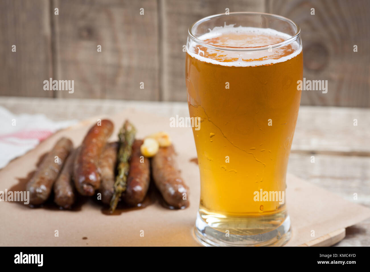 Gebratene Würstchen und Tasse kaltes Bier auf einem Holztisch. top View Stockfoto