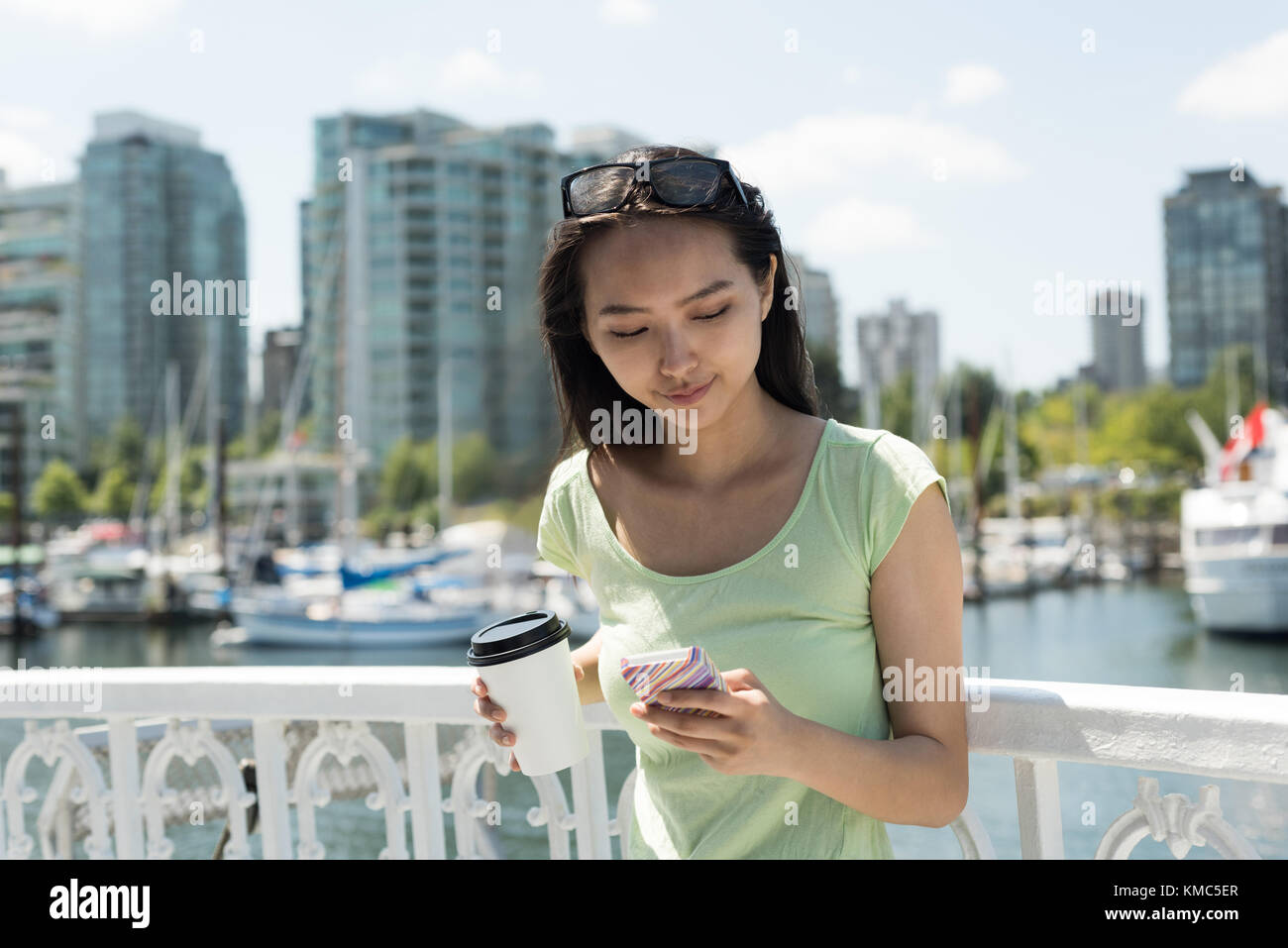 Asian Woman mit Kaffeetasse über ihr Handy in der Fähre Stockfoto