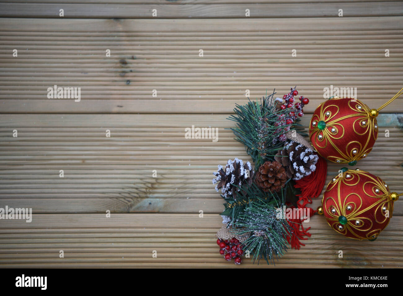 Weihnachten fotografie Bild mit roten und grünen Christbaumkugel Dekorationen und Tannenzapfen mit Niederlassungen mit Schnee auf rustikalem Holz Hintergrund Stockfoto