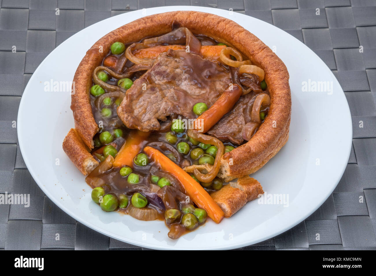 Ein gefüllter Yorkshire-Pudding mit geschnittenem Rindfleisch, Gemüse und einer dicken Soße. Stockfoto