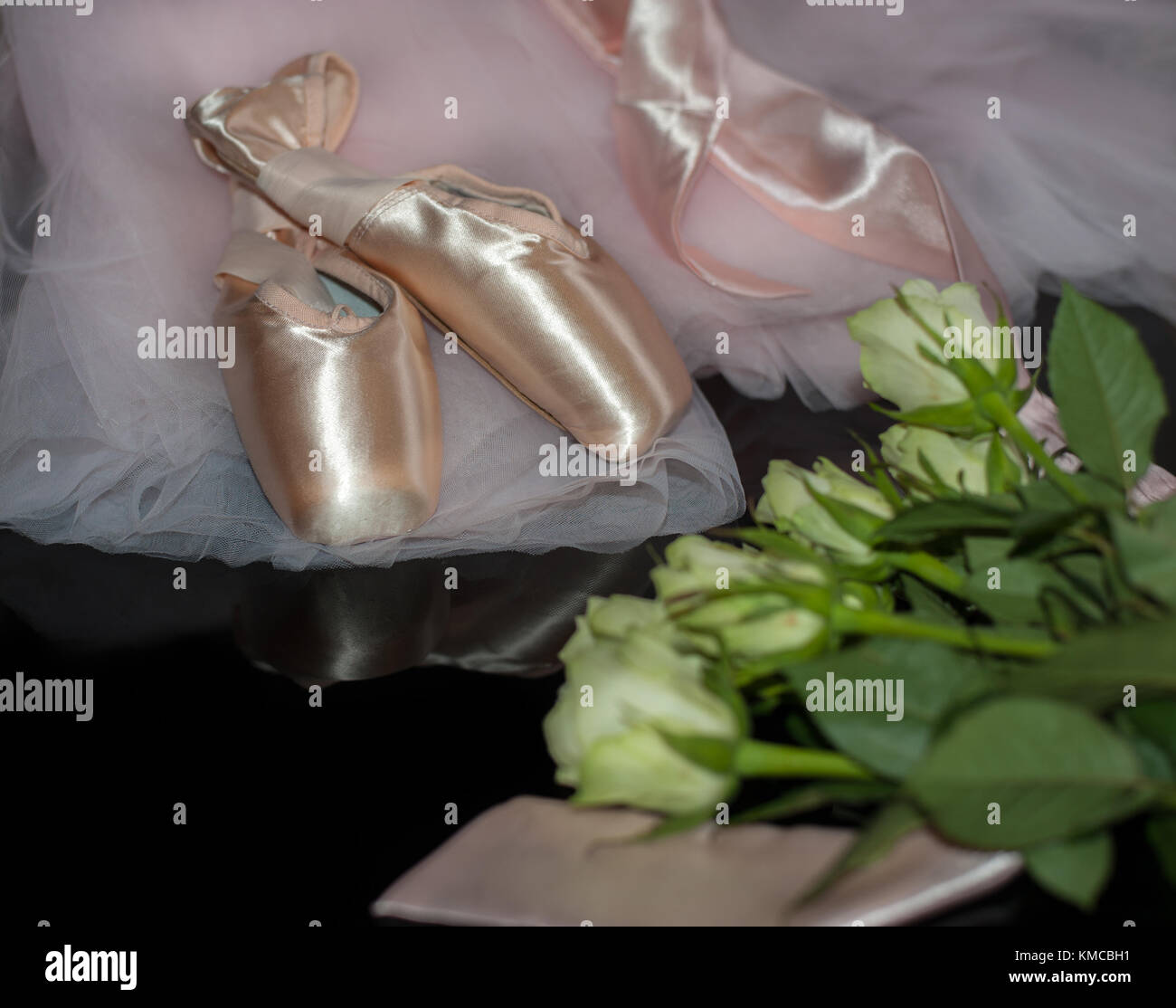 Satin Ballet Shoes, rosa Tutu und rosa Blüten auf schwarzem reflektierenden Hintergrund Stockfoto