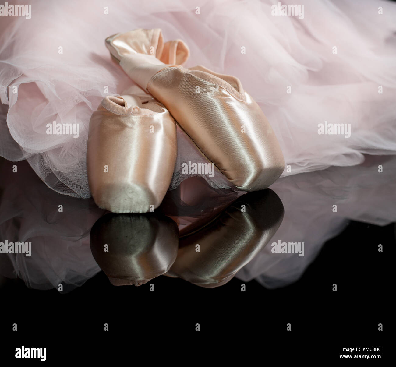 Satin Ballett Spitzenschuhe und rosa Tutu auf Schwarz reflektierenden Hintergrund Stockfoto