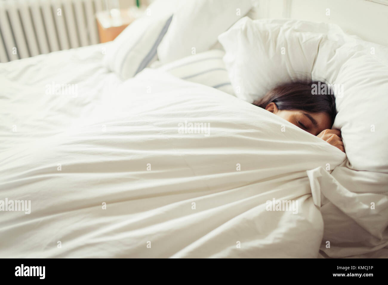 Müde junge Frau schläft im Bett Stockfoto