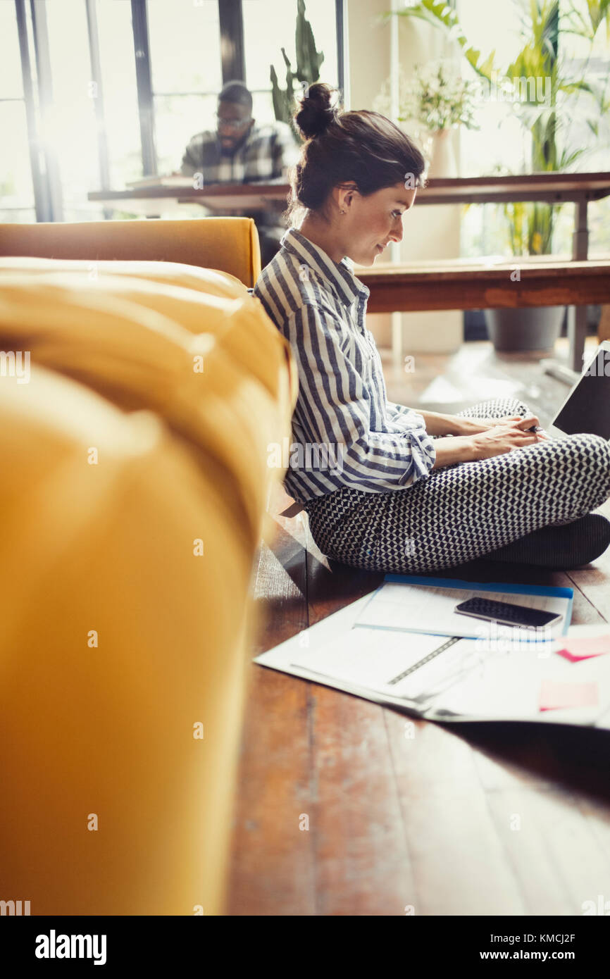 Freiberufliche Mitarbeiterin, die am Laptop im Wohnzimmer arbeitet Stockfoto