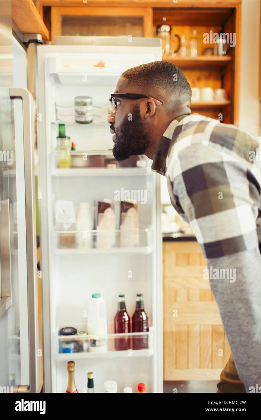 Junger Mann gucken in den Kühlschrank Stockfoto