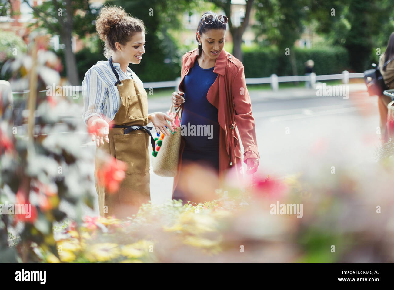 Weibliche Floristin hilft schwangeren Shopper an Blumengeschäft Schaufenster Stockfoto