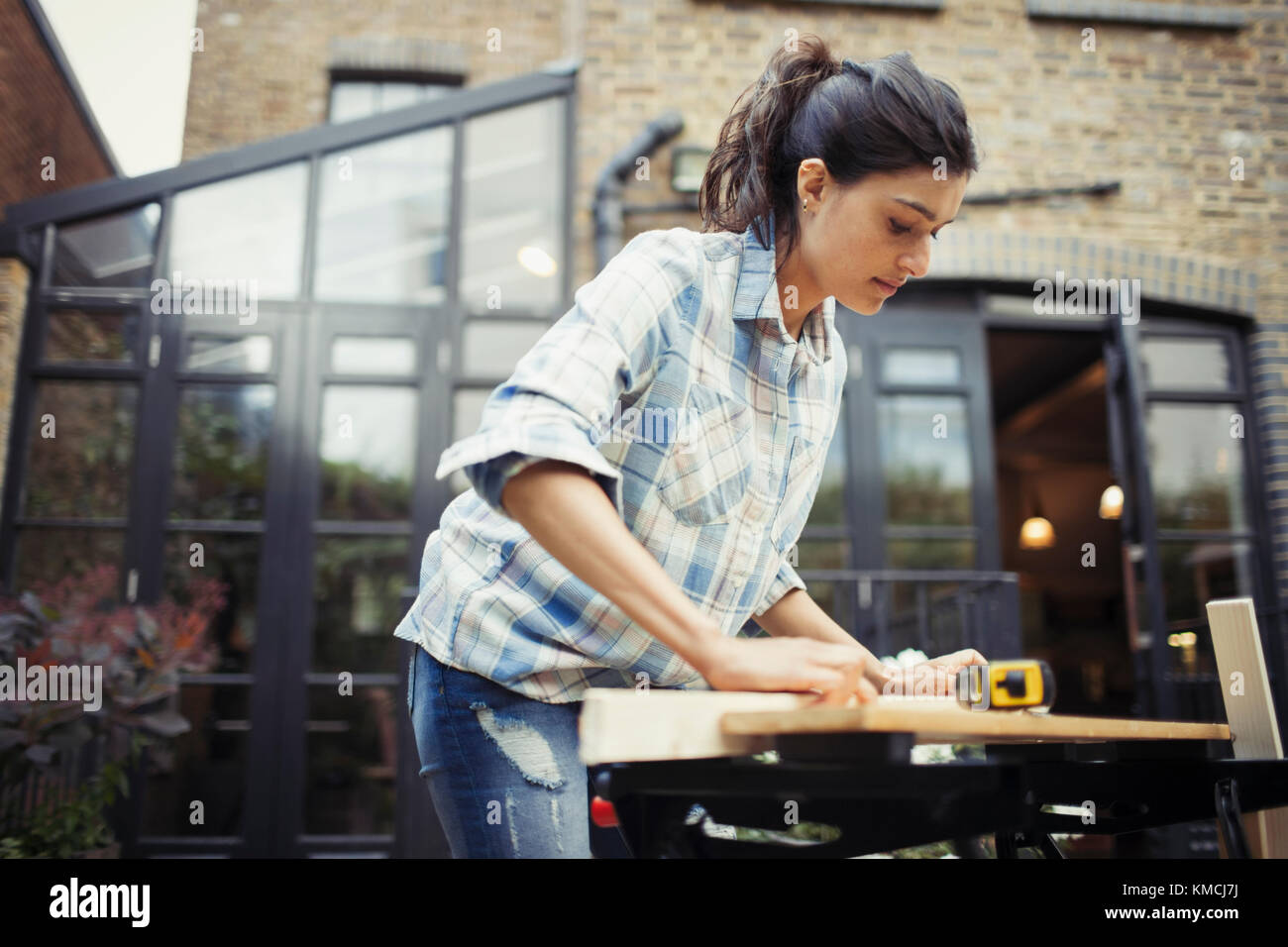 Junge Frau, die Holz auf der Terrasse misst Stockfoto