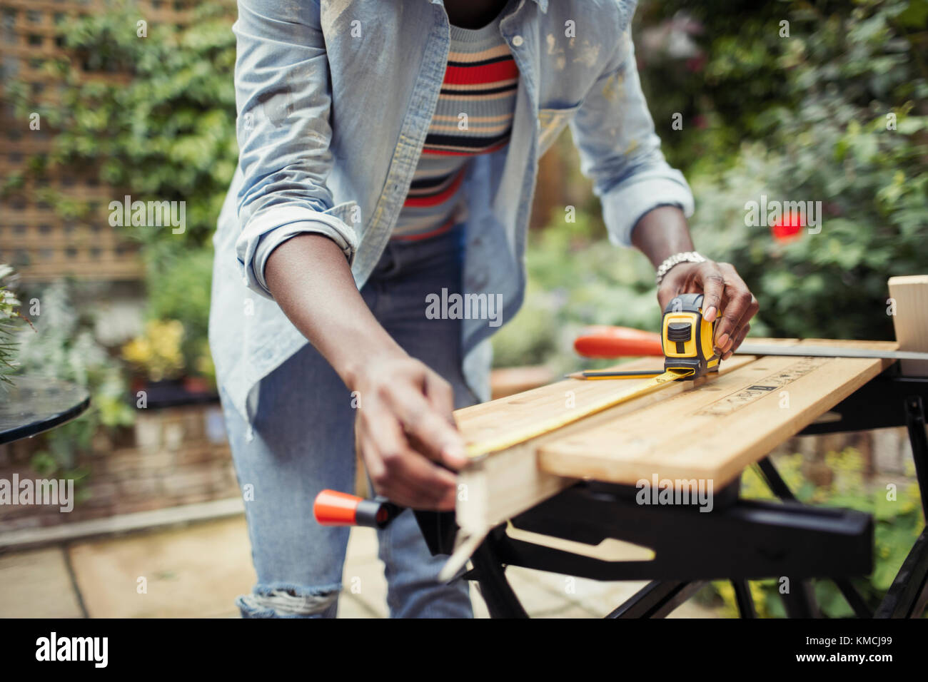 Frau mit Maßband, die Holz auf der Terrasse misst Stockfoto