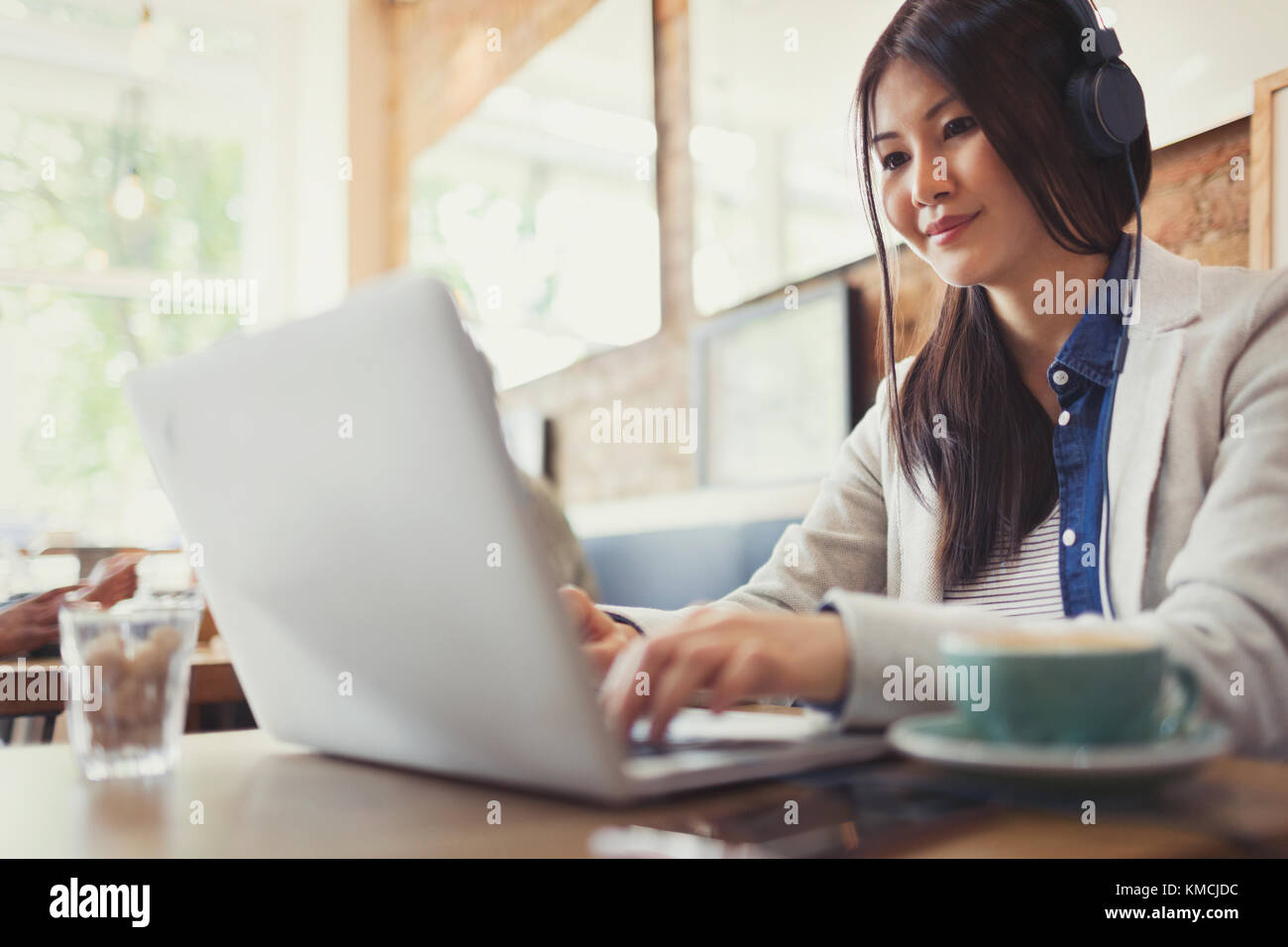 Junge Frau mit Laptop und Kaffee trinken im Café Stockfoto