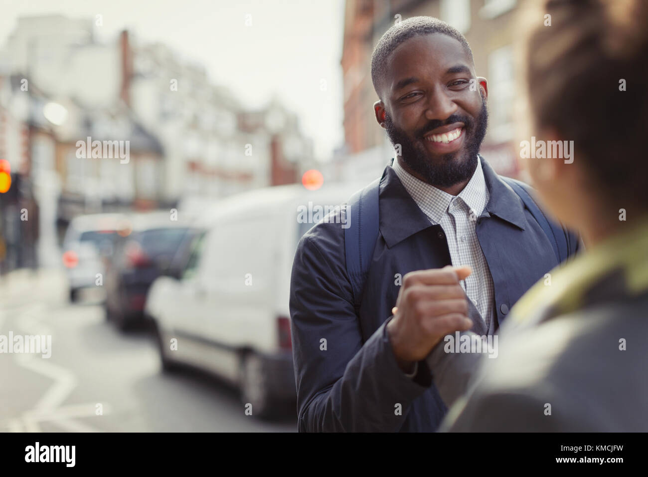Lächelnder Geschäftsmann schüttelt sich die Hände mit Kollegen auf der städtischen Straße Stockfoto