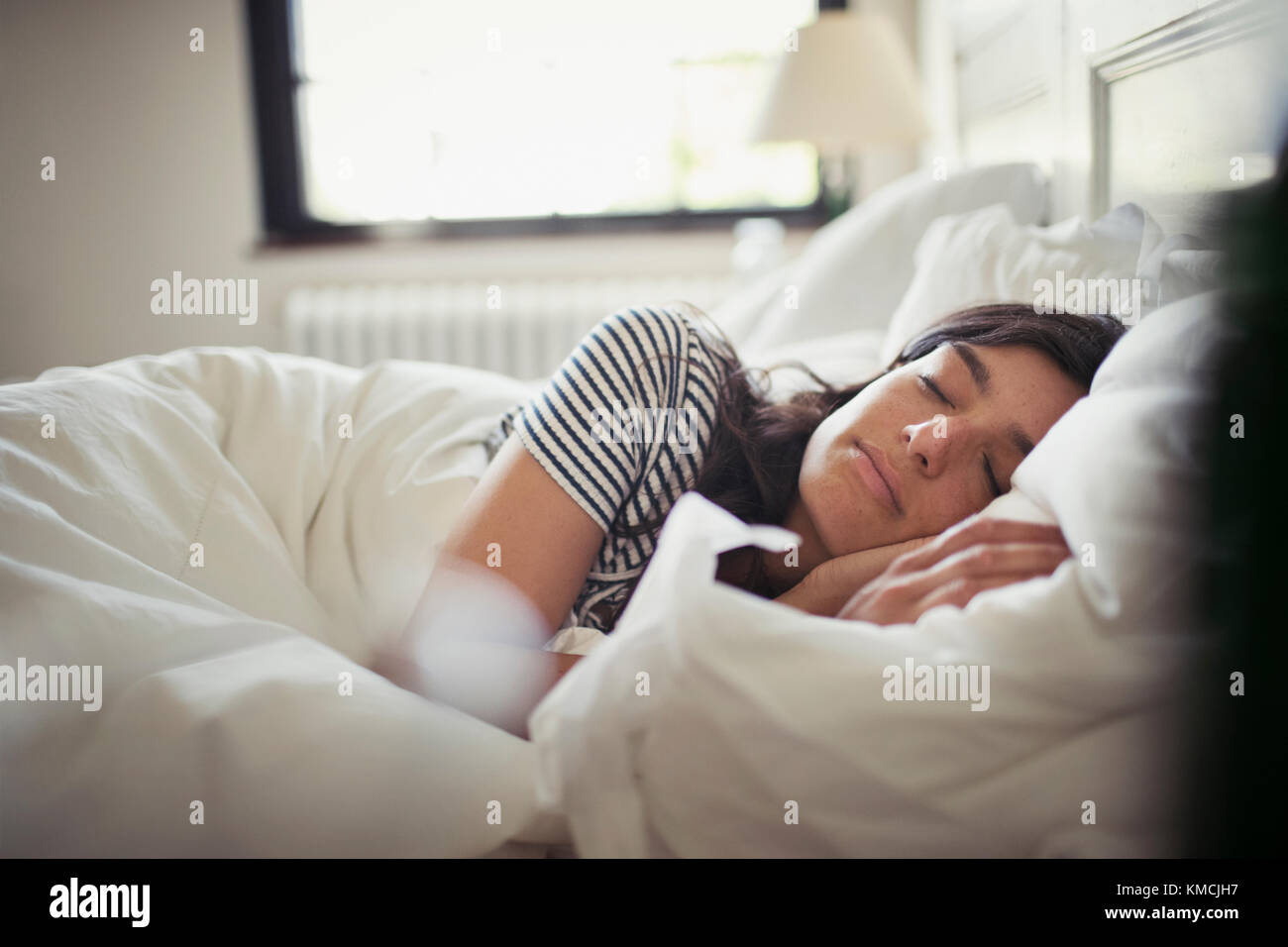 Müde, ruhige junge Frau, die im Bett schläft Stockfoto