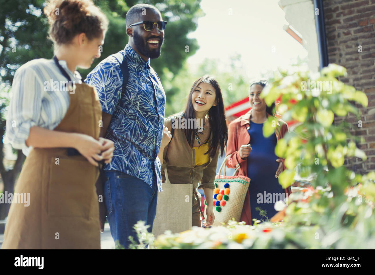 Weibliche Floristin hilft Freunden an sonnigen Blumengeschäft Schaufenster Stockfoto