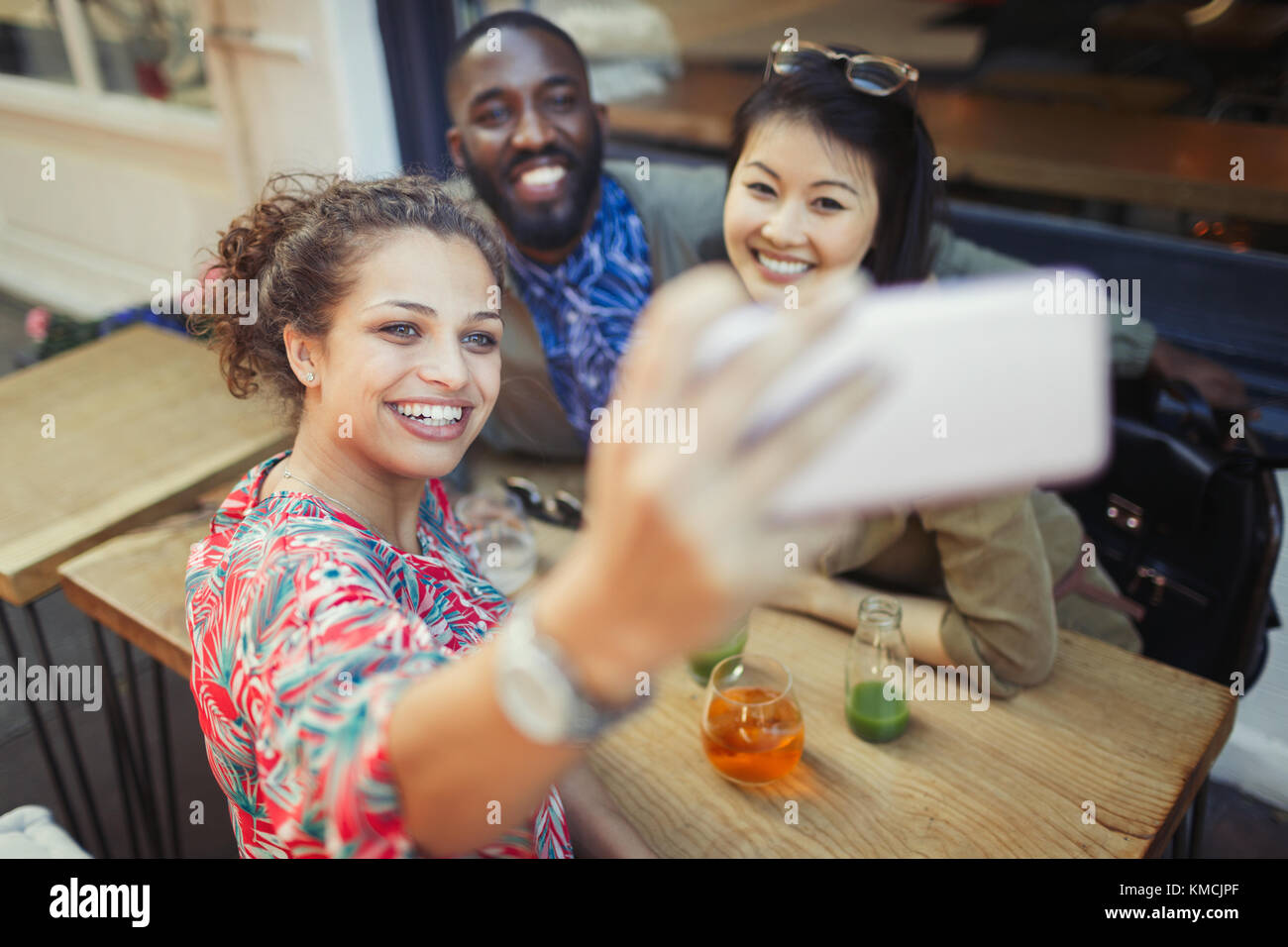 Lächelnde junge Freunde, die Selfie mit dem Kameratelefon auf dem Bürgersteig machen Café Stockfoto