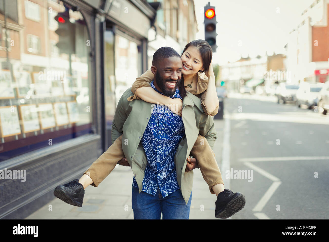 Verspielte junge Paar Huckepack auf städtischen Straße Stockfoto