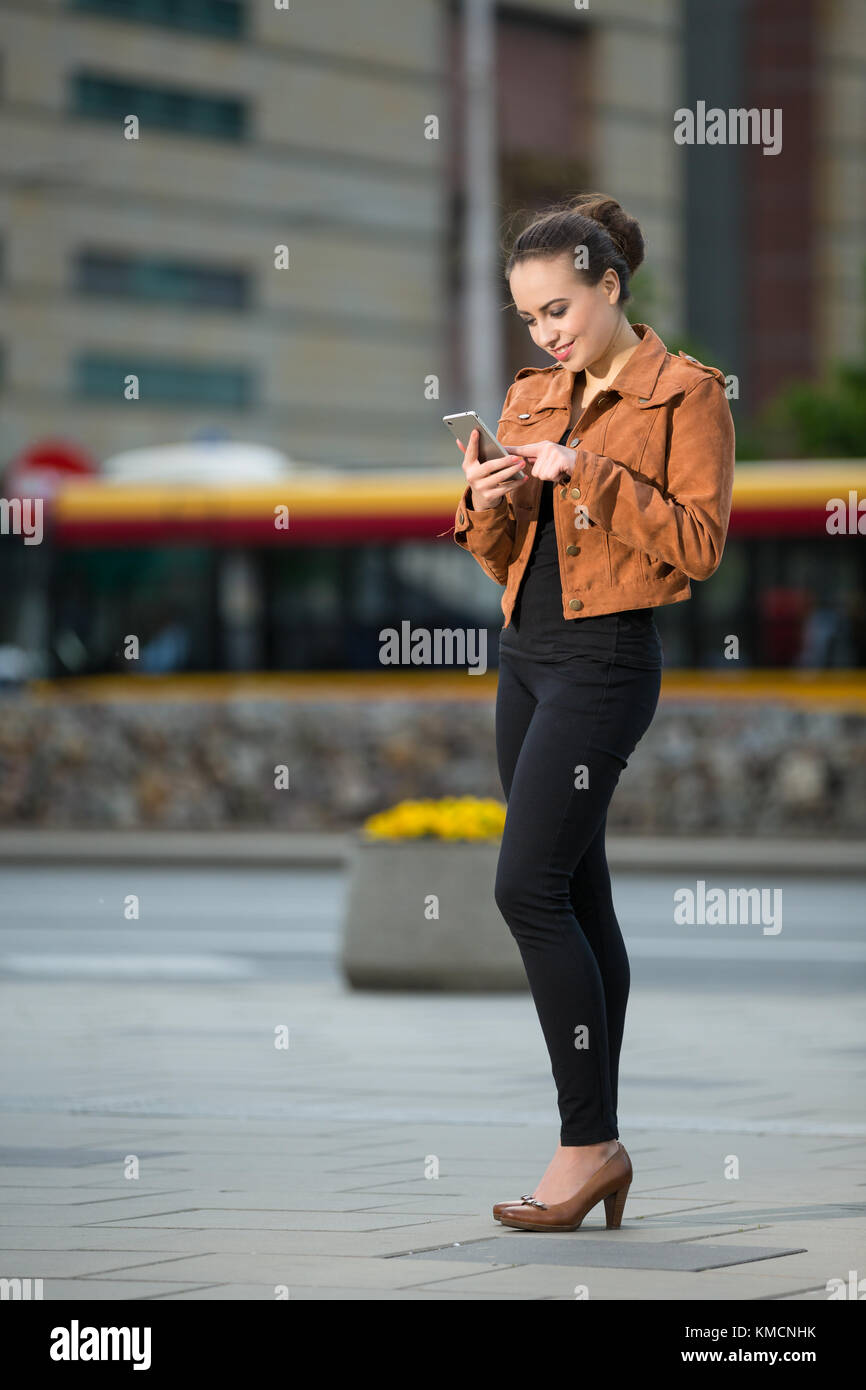 Junge Frau liest eine SMS auf ein Handy im Stadtzentrum Stockfoto