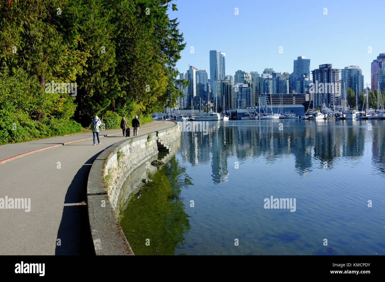 Fußgänger zu Fuß rund um den Rand der Stanley Park mit dem Vancouver Skyline im Hintergrund. Stockfoto