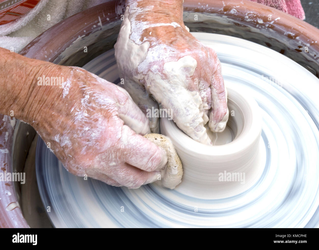 Hände von einer älteren Frau werfen Tonwaren auf Keramik Rad Stockfoto